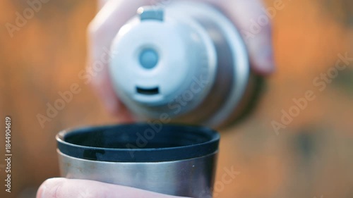 Hot Drink Pouring from Thermos into Metal Cup | Extreme Close-Up of Outdoor Camping Beverage with Autumn Leaves Background | Hiking and Adventure Lifestyle Concept