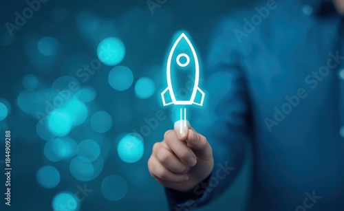 Hand holding glowing rocket launch icon on blue bokeh background for startup business and technology innovation concepts representing growth
