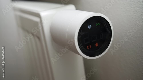 Male hand adjusting radiator thermostat to raise room temperature.