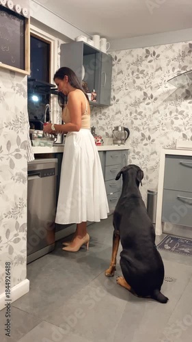 Woman Doing Chores in Kitchen with Loyal Dog Sitting Patiently Nearby