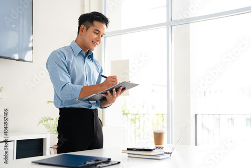 Young man in an office setting reviews documents attentively.