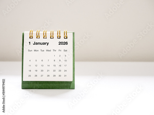 Minimal green desk calendar showing January 2026 page, with clean background and soft lighting. Perfect for business, planning, time management, and new year-related concepts in modern workspace.