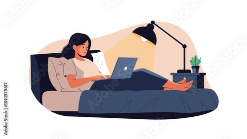 Young woman relaxing in her bed at night, comfortably working or studying on her laptop under the warm glow of a desk lamp.