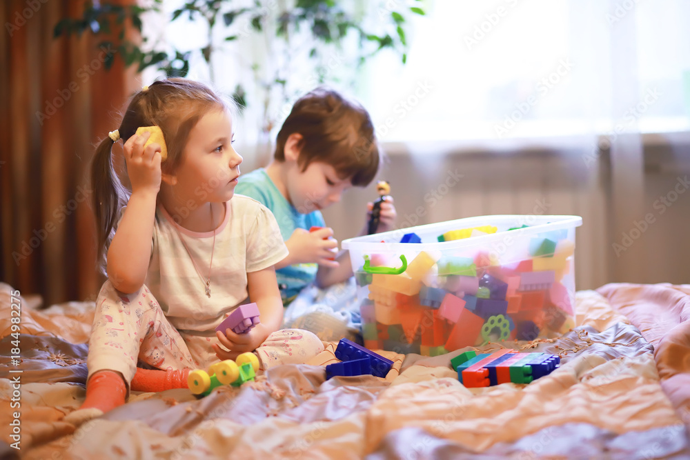 Fototapeta premium Children play construction set sitting on the sofa and watch cartoons on TV.