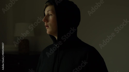 Person in hoodie with blue and red light, eerie mood, mysterious scene