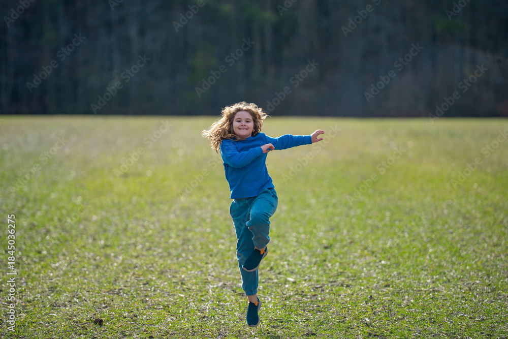 Fototapeta premium Child running on field. Happy kid running outdoors. Child jumping and running in nature. Kid running in a meadow. Summer fun for active child. Playful kid freedom. Carefree childhood in nature.