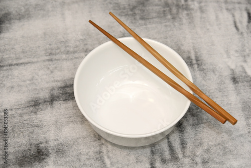 Empty bowl on table with chopsticks