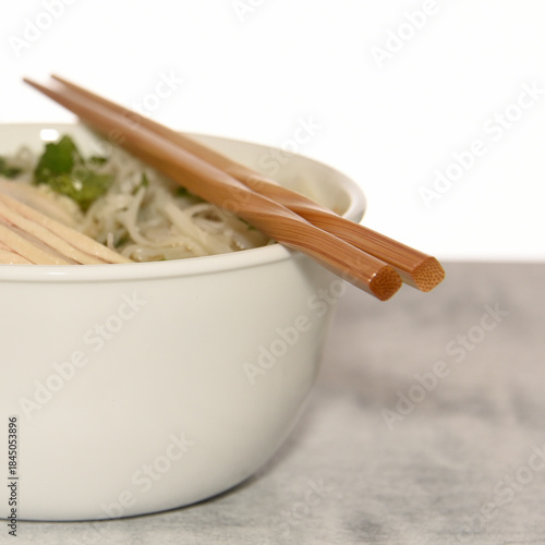 Bowl with chicken pho with chopsticks