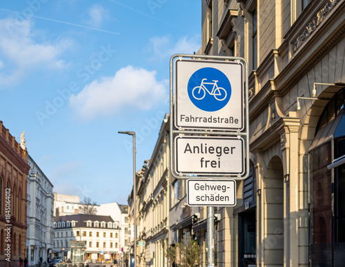German road signs marking a bicycle-priority street (Fahrradstraße), local access only (Anlieger frei) and a sidewalk damage warning (Gehwegschäden) in Berlin on a sunny day
