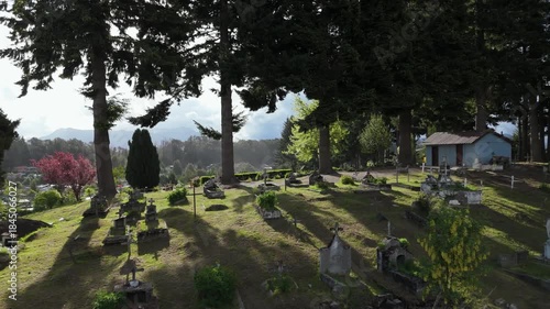 Aerial view of the cemetery in Villa La Angostura, Patagonia, Argentina, surrounded by forest and greenery. The image evokes themes of death, remembrance, religion, spirituality, and peaceful 