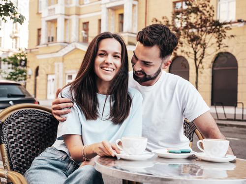 Smiling beautiful woman and her handsome boyfriend. Happy cheerful family. Couple drinking coffee in restaurant. They drinking tea at cafe in the street. Holding cup. Enjoying their date