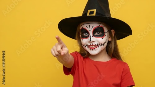 Child with sugar skull makeup pointing finger.