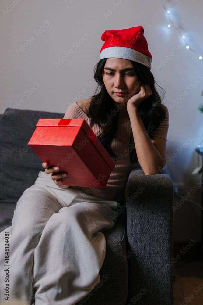Fototapeta premium Woman feeling disappointed holding christmas gift during holiday