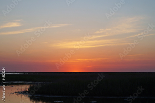 Sunrise over a lake surrounded by tall grass on a warm summer day