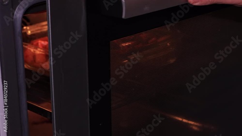 Preparing baked pumpkin in the oven, a delicious autumn dish made with pumpkin, feta cheese, and olive oil, a healthy and nutritious meal, with hands closing the oven door.