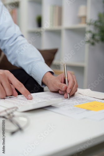 Tax Filing. Close-up of individual reviewing tax documents and making calculations.