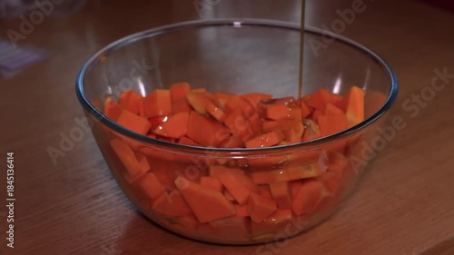 Preparing baked pumpkin in the oven, a delicious autumn dish made with pumpkin, feta cheese, and olive oil, a healthy and nutritious meal, with hands mixing the ingredients in a glass bowl.