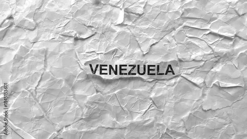 Crumpled piece of paper with word Venezuela on torn crumpled white paper pieces background