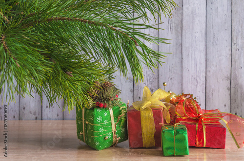 Christmas holiday greeting card template; Pine branch and gift boxes on a wooden background; copy space