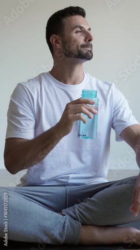 Athletic man drinking water after yoga workout