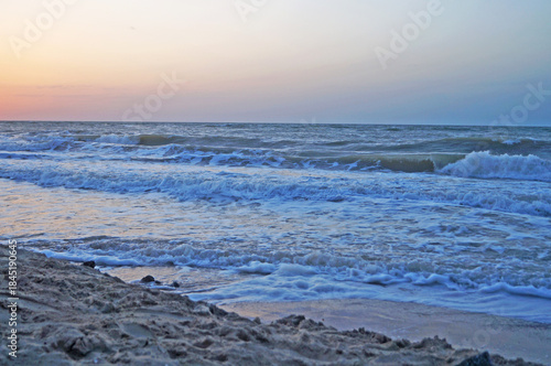 View of the sea from the coast on waves with foam on a summer day