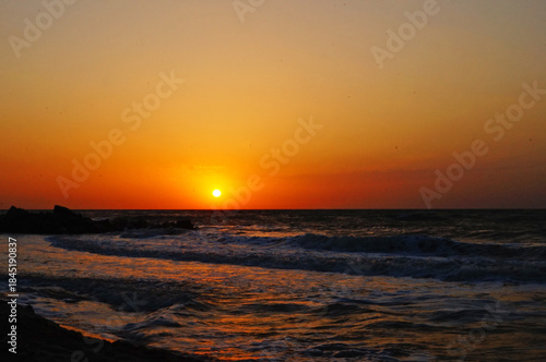 Sunrise on the seashore with waves on a warm summer morning