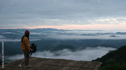 A woman set up a camping chair, sitting and looking at a beautiful foggy mountain before sunrise