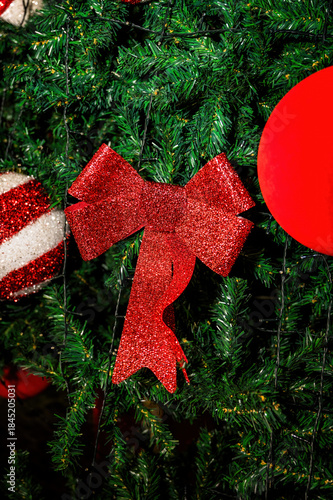 Festive Christmas tree decorated with red bows and ornaments under night sky with bright fireworks explosion above, holiday celebration outdoors, New Year atmosphere, winter festival mood