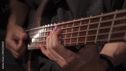 Close up of finger musician at the bass guitar , musician playing bass guitar in the room and with  spotlights ,Bassist practicing in a studio.