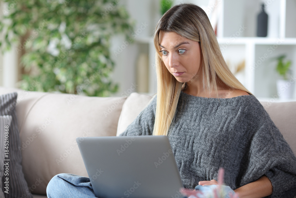 Naklejka premium Perplexed woman checking online content on laptop at home