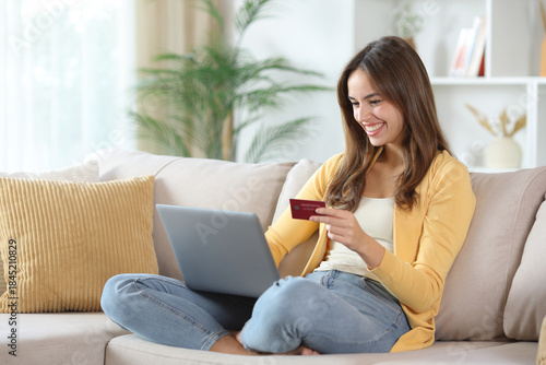 Foto Happy woman in yellow paying online at home