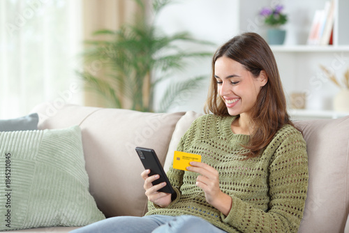 Happy woman in green buying online with card at home