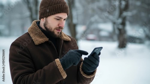 Man in winter clothes uses smartphone outdoors
