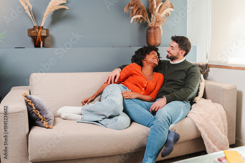 A loving couple sharing tender moments while sitting comfortably on a plush sofa in their warm home. The intimate setting is perfect for expressing love and connection in a cozy living space.