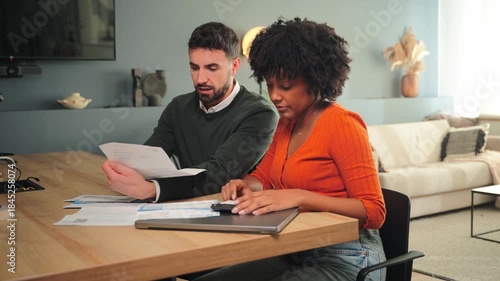 A happy couple engaged in online shopping together using a laptop and a credit card in their cozy home. They are excited about their purchases and enjoying the process of shopping together.