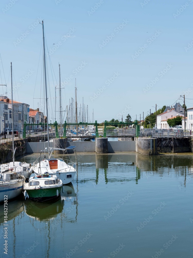 Fototapeta premium Marans in Charente-Maritime, river and sea town between marsh and sea. Lock between Quai Maréchal Foch and Quai des Fusilliers Marins on the Sèvre Niortaise canal 