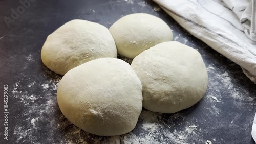 Close up of small yeast dough balls on floured kitchen table, rest and proofing preparation concept 