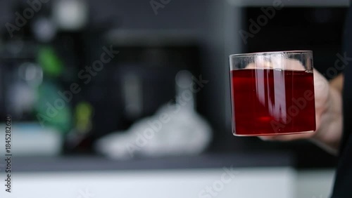 Close up of female hand holding a glass cup with hot tea, blurred background