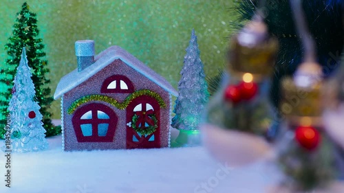 On a brown background, a small house with Christmas trees nearby and large light bulbs in the foreground