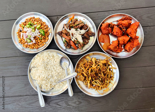 Traditional Nepali food platter with spicy fried snacks, beaten rice, peanuts and meat dishes served on steel plates. Ideal for travel, culture, hospitality, restaurant menus and food blogs.