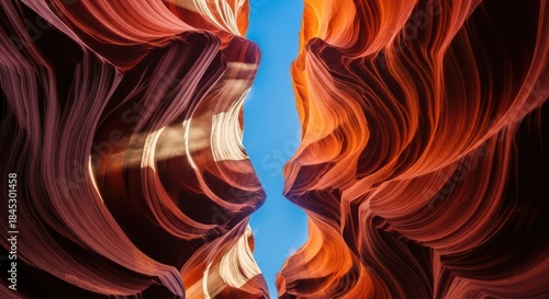 Vibrant antelope canyon walls illuminated by sunlight with a narrow blue sky above