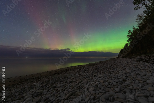 Fototapeta Naklejka Na Ścianę i Meble -  Vibrant Aurora Borealis Over the Baltic Sea and Stony Beach at Night on the Paldiski Peninsula, Estonia.