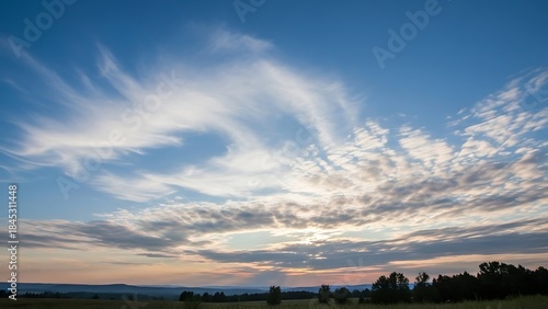 Beautiful sunset sky over mountains and fields with orange clouds reflecting on a calm river at dusk during a summer evening landscape