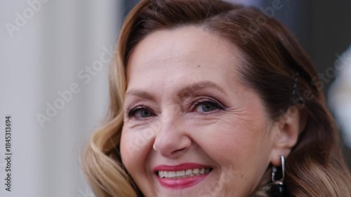 A woman with a smile on her face. She has a pair of earrings and a braid in her hair