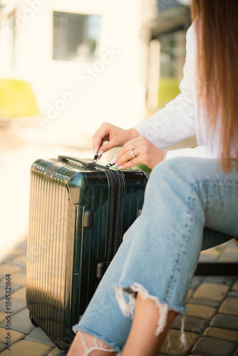 closeup unrecognizable woman open suitcase sitting at bus stop in trip