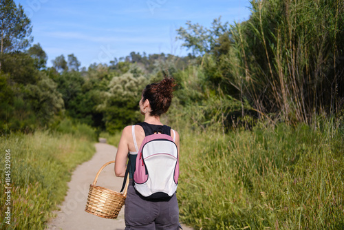 Canvas Print rear view of Woman hiking in nature path carrying basket backpack