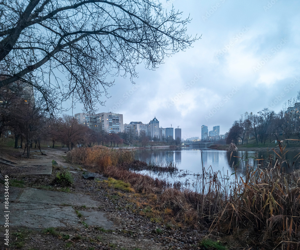 Obraz premium City skyline reflecting on park lake during autumn twilight