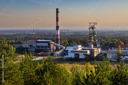 Fotografie The buildings, chimney and shaft tower of the disused Boże Dary mine illuminated by the setting sun