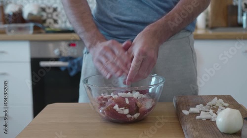 Man Adding Chopped Onion to Raw Meat in a Glass Bowl for Marinating