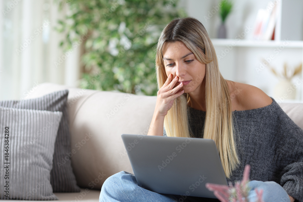 Naklejka premium Concentrated woman watching online content on laptop at home